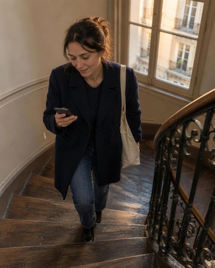 Fin de journée, une femme monte l'escalier de son immeuble parisien